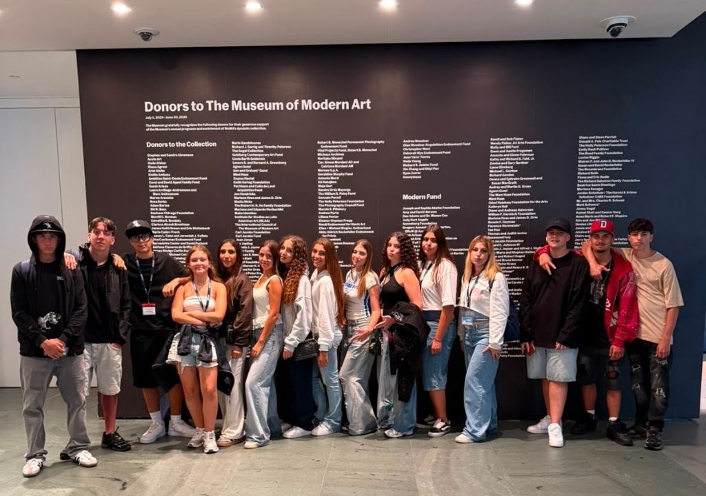 Gruppo di studenti in posa davanti al Donor Wall all'interno del MoMA di New York durante un soggiorno studio negli Stati Uniti
